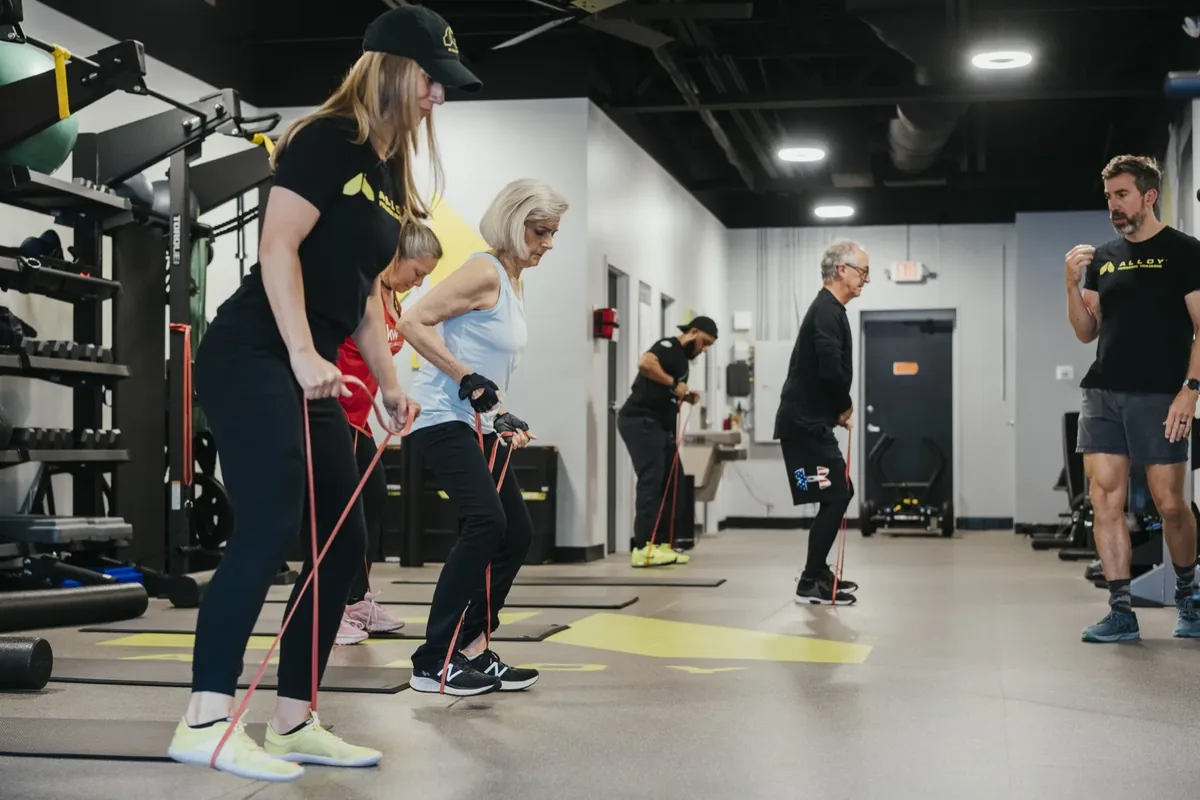 Coaches leading a small group of members through banded hip hinges at Alloy Ahwatukee Foothills