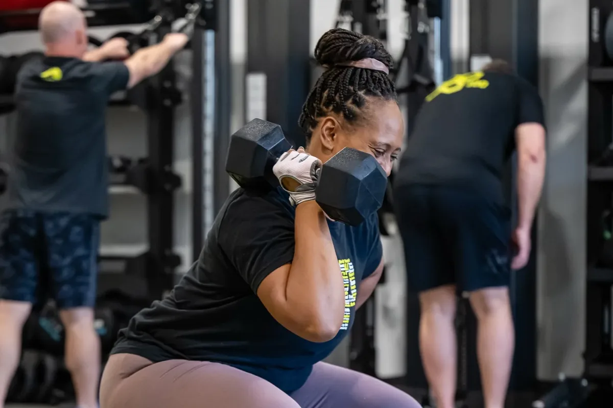 Member squatting with a dumbbell during a coached session at Alloy Ahwatukee Foothills